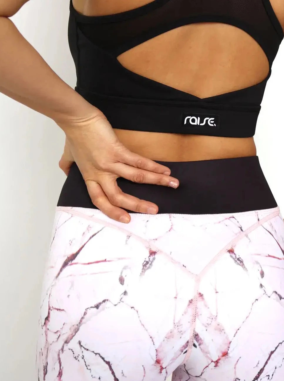Rückseite von sportlicher Frau in rosa Sport Leggings und schwarzem Sport BH von raise Sportswear
