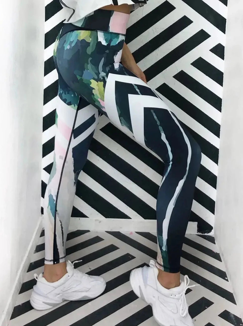 Seitenansicht von bunter Sportleggings von raise Sportswear vor schwarz weiß gestreifter Wand